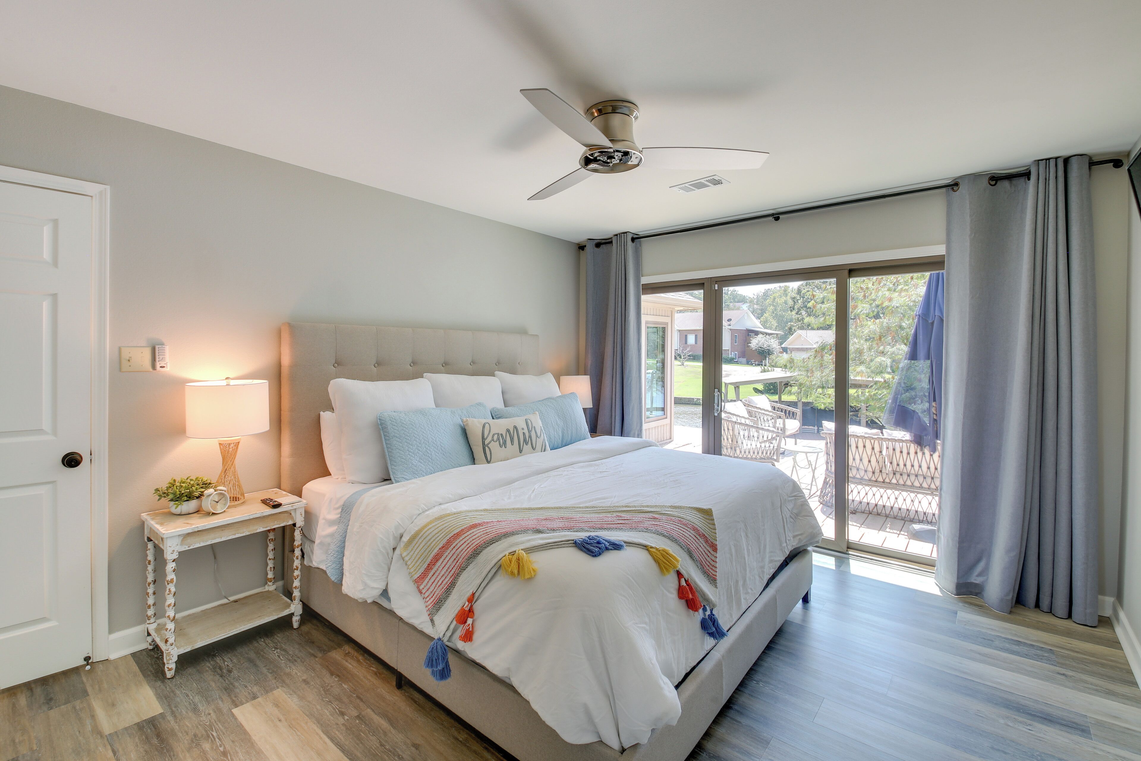 A bedroom with a large bed, a bedside table with a lamp, and a ceiling fan.