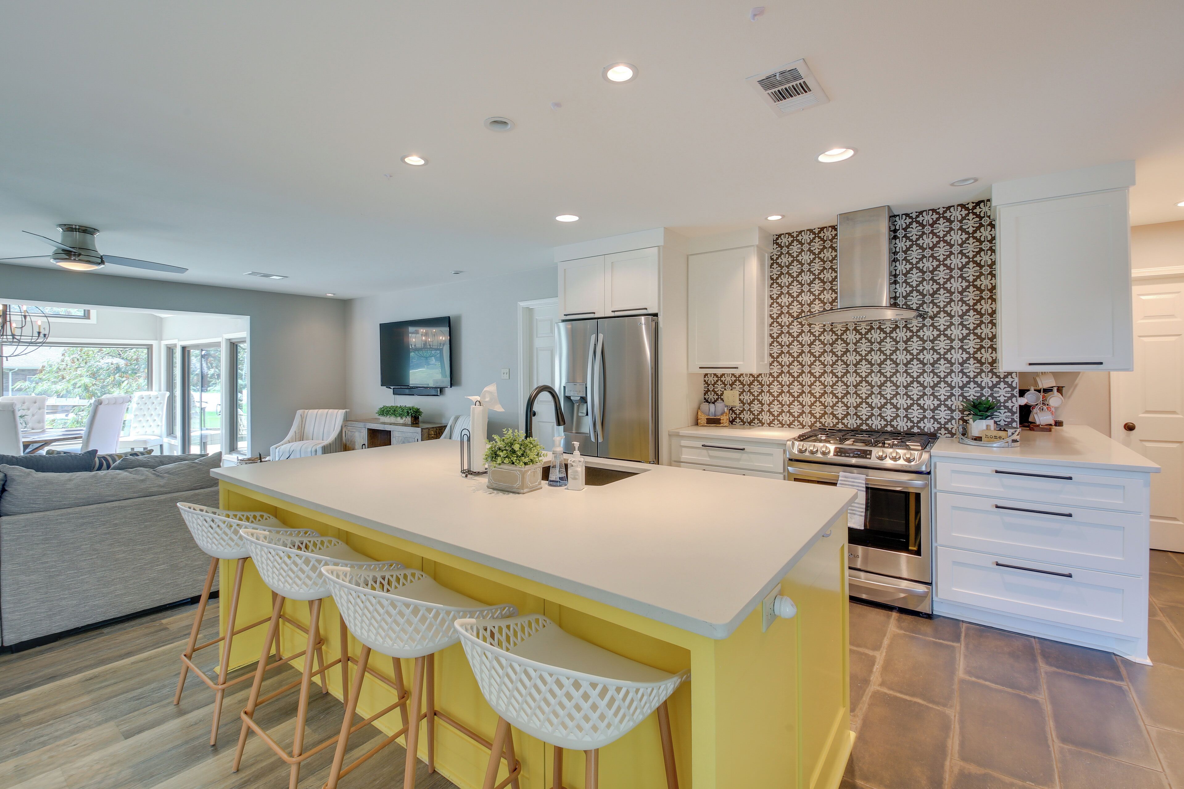 A modern kitchen with a central island, bar stools, a built-in oven, and a large refrigerator.