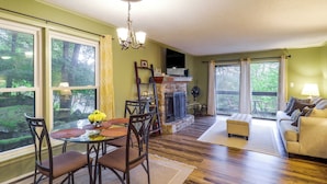 A living room with a fireplace, dining area, and a sofa. - Walk to Slopes! Beech Mountain Condo, Pet Friendly (Banner Elk)