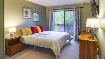 A bedroom with a bed, nightstand, dresser, and a window with curtains.