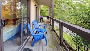 A wooden deck with blue Adirondack chairs and a table, overlooking a lush green landscape. - Walk to Slopes! Beech Mountain Condo, Pet Friendly (Banner Elk)