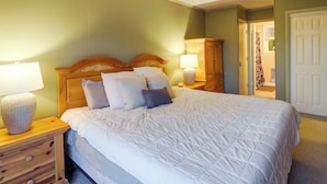 A bedroom with a large bed, wooden headboard, two bedside tables with lamps, and a wardrobe. - Walk to Slopes! Beech Mountain Condo, Pet Friendly (Banner Elk)
