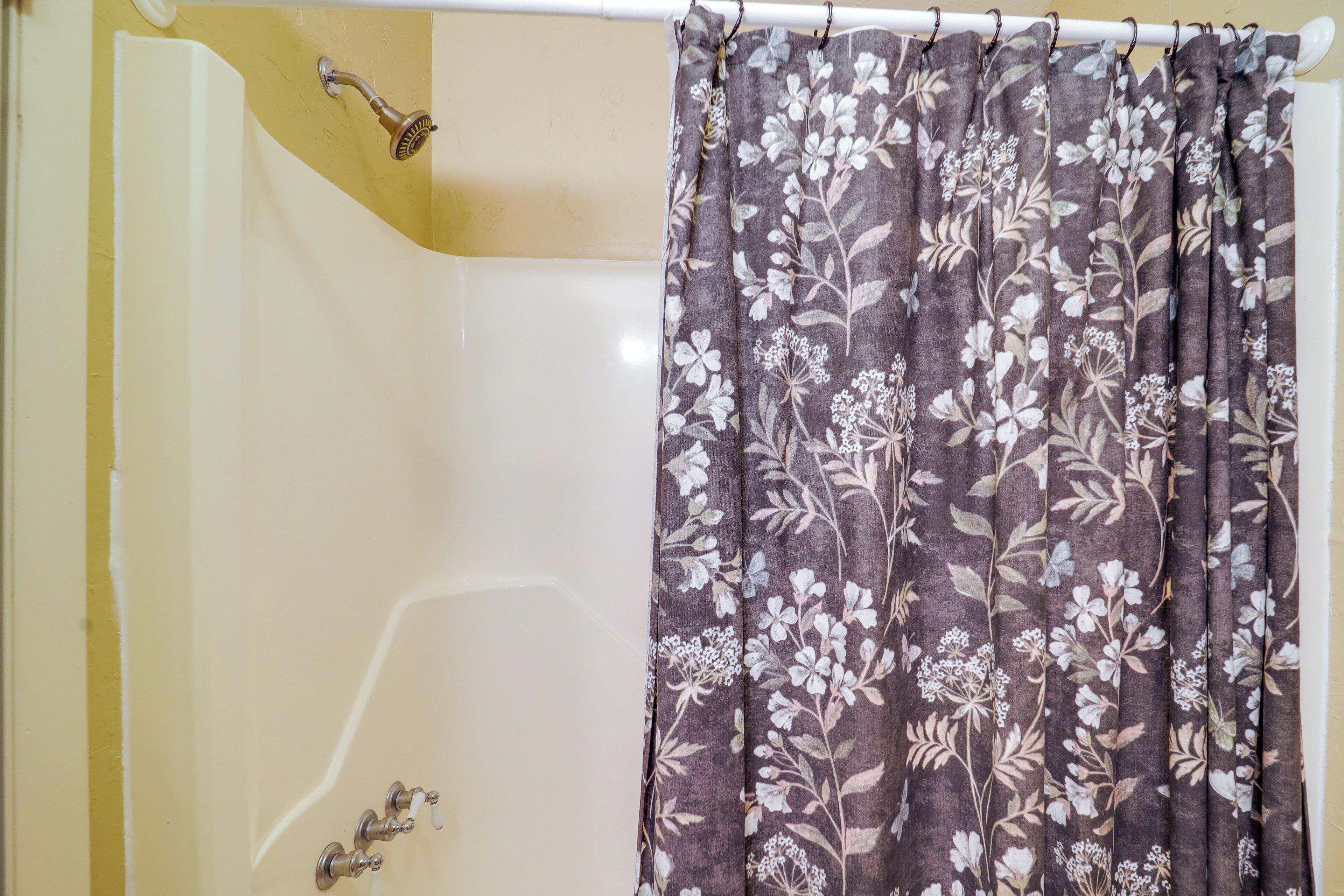 A bathroom with a bathtub, shower curtain, and faucet.
