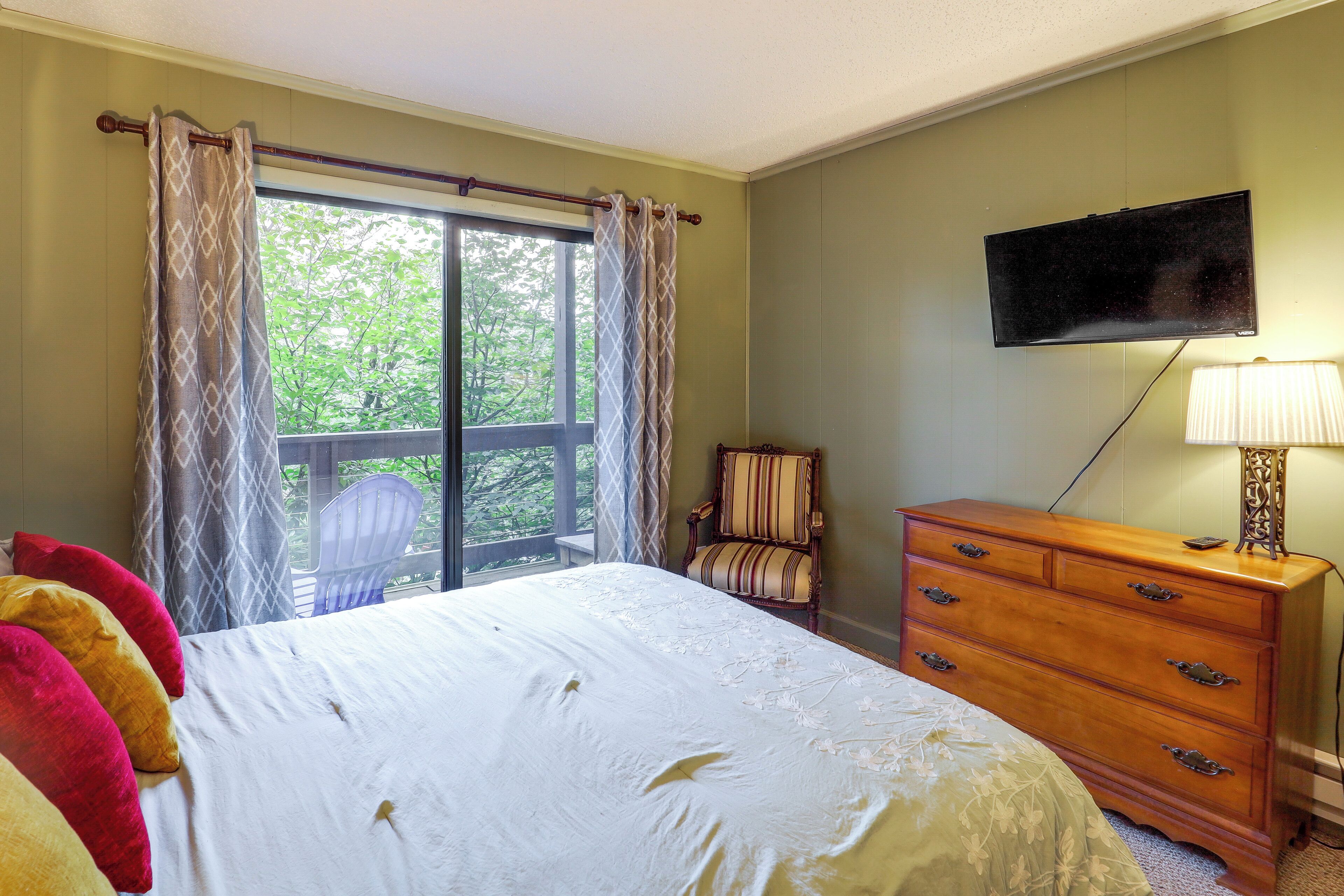 A bedroom with a bed, a dresser, a chair, a television, and a window with curtains.