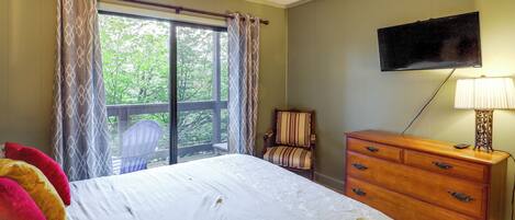 A bedroom with a bed, a dresser, a chair, a television, and a window with curtains.