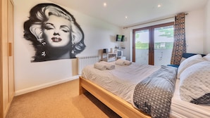 Un dormitorio con una cama grande, un mural en la pared, un televisor, una ventana con cortinas y un radiador.