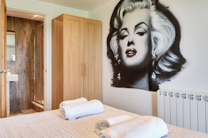 A hotel room with a large bed, a wooden wardrobe, and a wall mural.