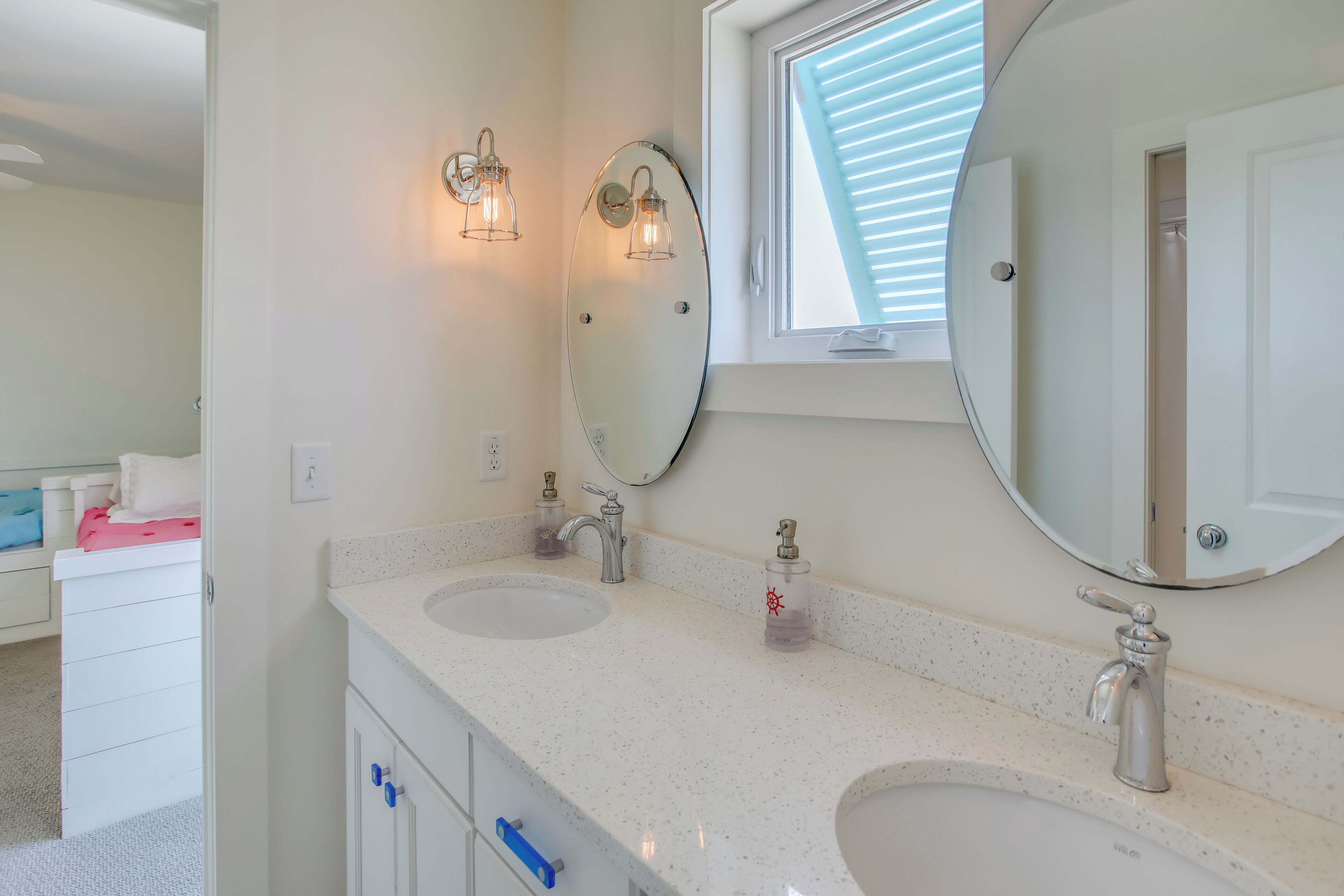 A bathroom with two sinks, a large mirror, and wall-mounted lights.