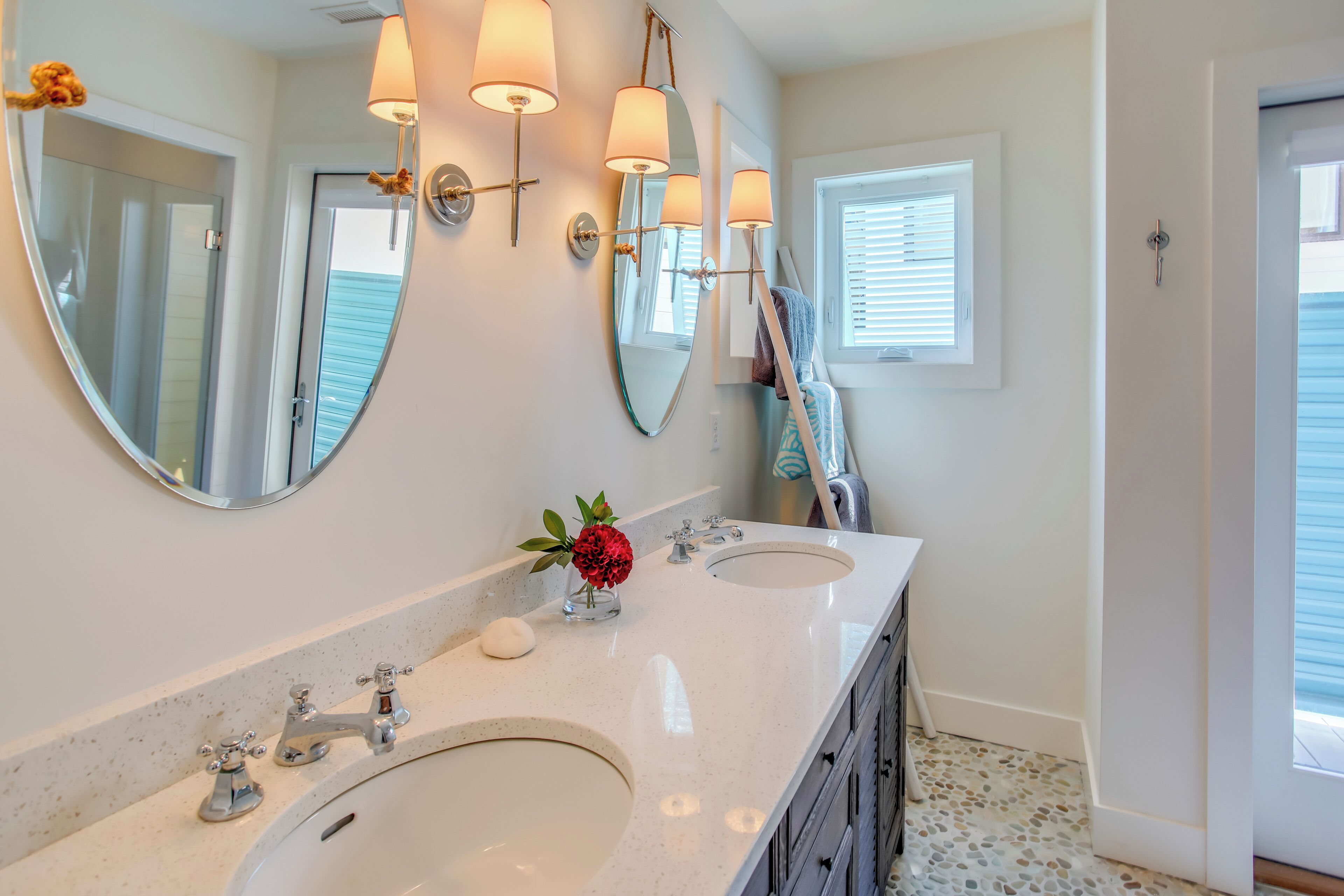 A bathroom with two sinks, a large mirror, and wall-mounted sconces.