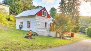 Une cabane en rondins avec un toit rouge et des murs blancs, une terrasse en bois et un escalier menant à un porche.