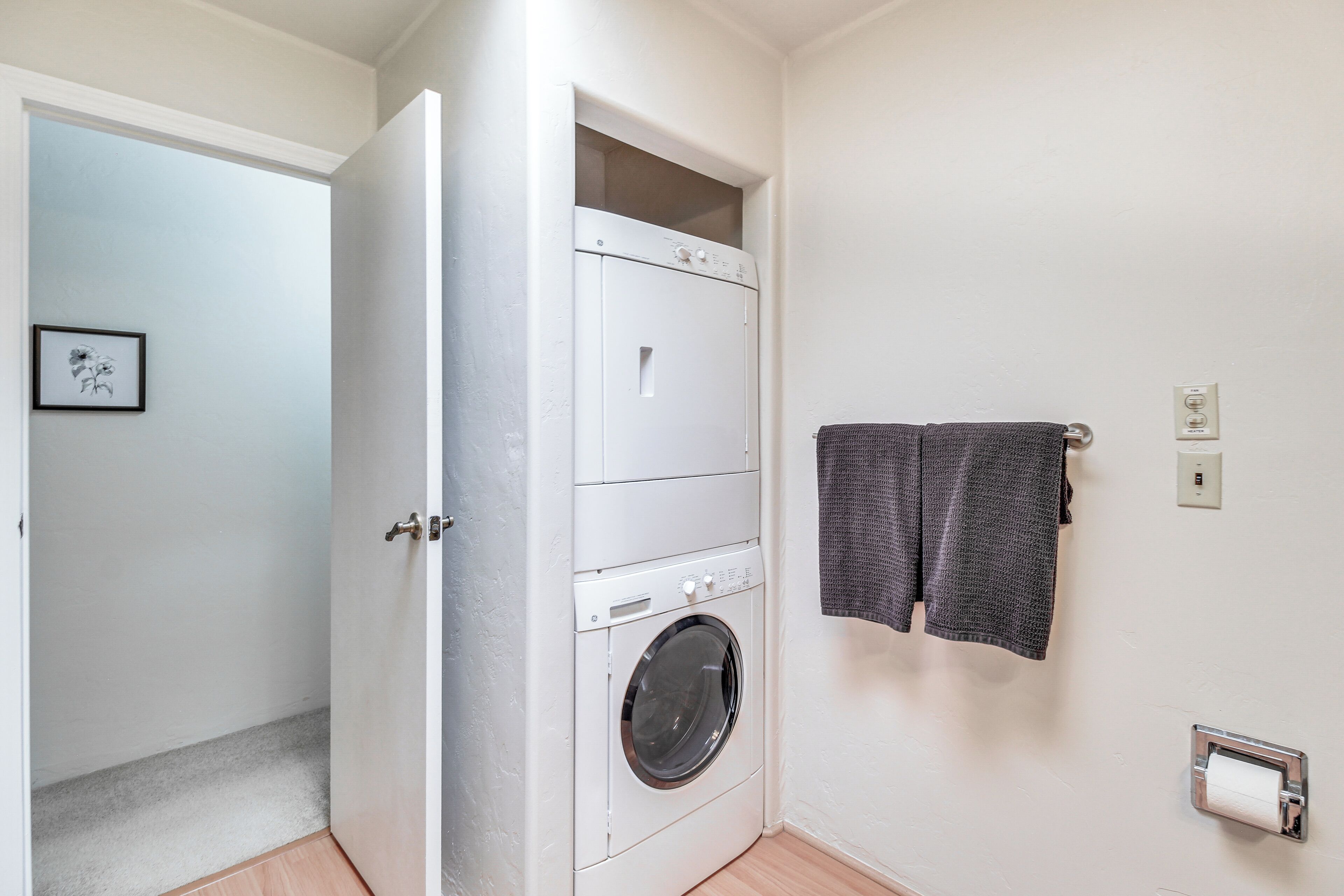 A laundry area with a washing machine, a drying rack, and a towel dispenser.