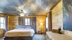 Une pièce de cabane en bois comprenant un lit, un ventilateur de plafond, une lampe et un panneau indiquant « Marché de producteurs ».