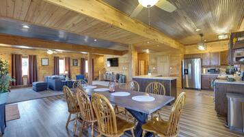 A spacious wooden cabin with a large dining area, kitchen, and living room.