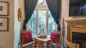 A cozy room with a wooden table and chairs, a fireplace, and a large window with curtains. - Wintergreen Resort Condo w/ Deck, 0.3 Mi to Slopes (Nellysford)