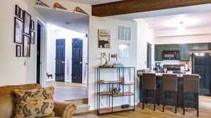 A spacious living room with a brown leather couch, a metal shelving unit, and a kitchen area with green cabinets and a refrigerator. - Wintergreen Resort Condo w/ Deck, 0.3 Mi to Slopes (Nellysford)