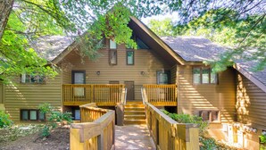 A wooden cabin with a wooden deck leading to a front door, surrounded by trees. - Wintergreen Resort Condo w/ Deck, 0.3 Mi to Slopes (Nellysford)