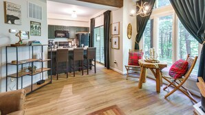 A modern kitchen with dark cabinets, a central island with bar stools, and a dining area with a wooden table and red plaid chairs. - Wintergreen Resort Condo w/ Deck, 0.3 Mi to Slopes (Nellysford)
