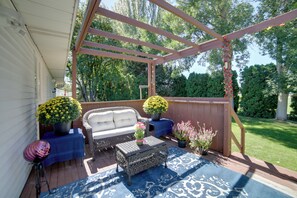 Une terrasse couverte avec un canapé, une table basse et des plantes en pot.