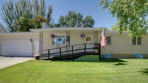 A two-story house with a front porch, a garage, and an American flag. - Simple + Charming Idaho Retreat w/ Patio! (Idaho Falls)