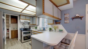 A modern kitchen with white cabinetry, a built-in oven, and a large island with seating. - Simple + Charming Idaho Retreat w/ Patio! (Idaho Falls)