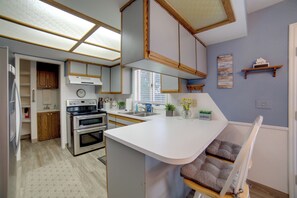 A modern kitchen with white cabinetry, a built-in oven, and a large island with seating. - Simple + Charming Idaho Retreat w/ Patio! (Idaho Falls)