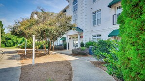 A white building with a green awning, a sidewalk, and a well-maintained garden area. - Greensboro Condo Rental Near Hospital & Trails! (Greensboro)