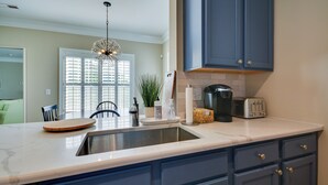 A kitchen with a sink, countertop, and blue cabinets. - Greensboro Condo Rental Near Hospital & Trails! (Greensboro)
