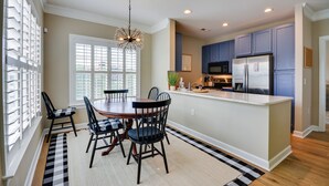A modern kitchen with a central island, dark blue cabinets, and a stainless steel refrigerator. - Greensboro Condo Rental Near Hospital & Trails! (Greensboro)