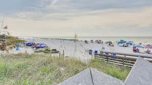 A beach with umbrellas, beach chairs, and a wooden walkway. - Bright Destin Condo w/ Community Pool! (Destin)