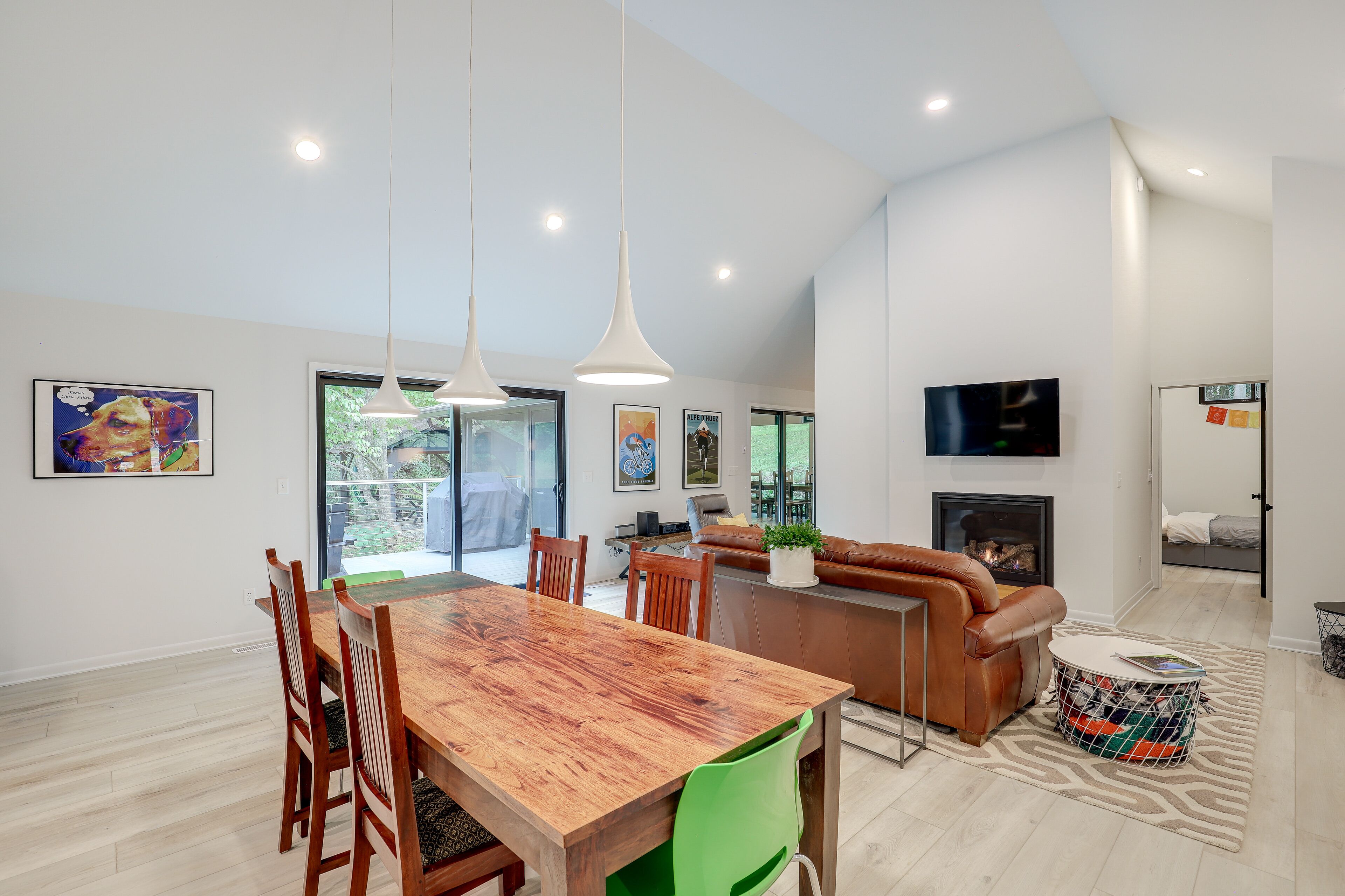 A spacious living room with a wooden dining table, leather sofa, and a fireplace.