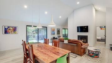 A spacious living room with a wooden dining table, leather sofa, and a fireplace.