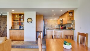 Una cocina moderna con armarios de madera, un comedor con mesa de madera y una estantería empotrada.