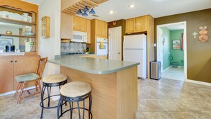 Una cocina moderna con armarios de madera, una isla central con taburetes, microondas y refrigerador.