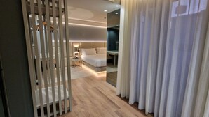 Une chambre d’hôtel moderne, équipée d’un lit, d’une table de chevet et offrant une vue à travers une paroi en verre.