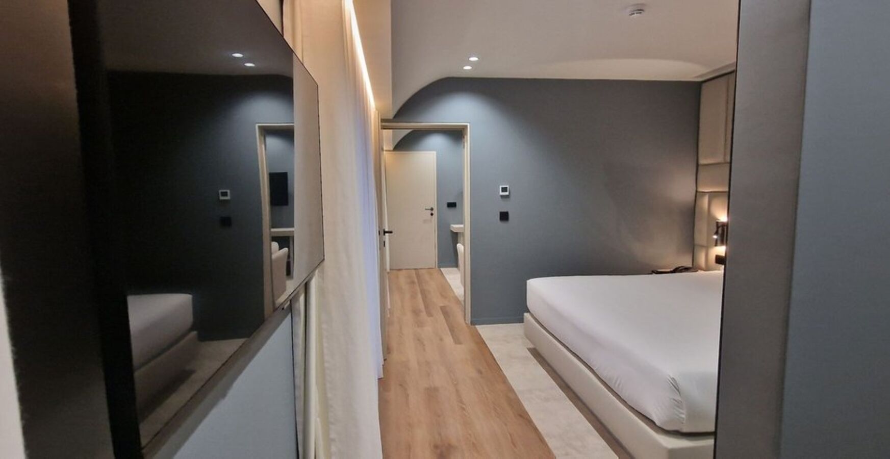 A modern hotel room with a bed, a small seating area, and a bathroom.