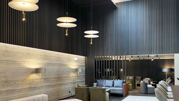 Un hall d’entrée moderne doté d’un espace salon aux lignes courbes, d’un éclairage suspendu et d’une combinaison de finitions en bois et en métal.