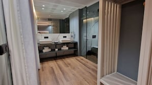 Une salle de bain moderne avec un plancher en bois, deux lavabos et un grand miroir.