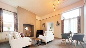 Un salon comprenant un canapé, un fauteuil, une table basse et un coin repas avec des chaises.