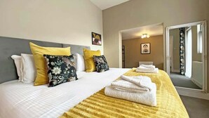 Une chambre d’hôtel avec un grand lit, une tête de lit et une couverture à rayures jaunes.
