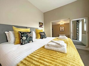 A hotel room with a large bed, a headboard, and a yellow striped blanket. - 2-Bed Victorian Elegance (Cheshire West and Chester)