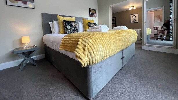 Une chambre moderne avec un grand lit, une table de chevet avec une lampe et un miroir.