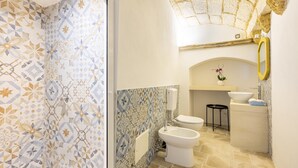 A bathroom with patterned tiles, a toilet, bidet, sink, and a mirror. - 3398 Leucadense - Grotta 3 by Barbarhouse (Castrignano del Capo)