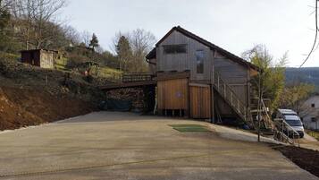 A two-story wooden building with a covered driveway and a small bridge.