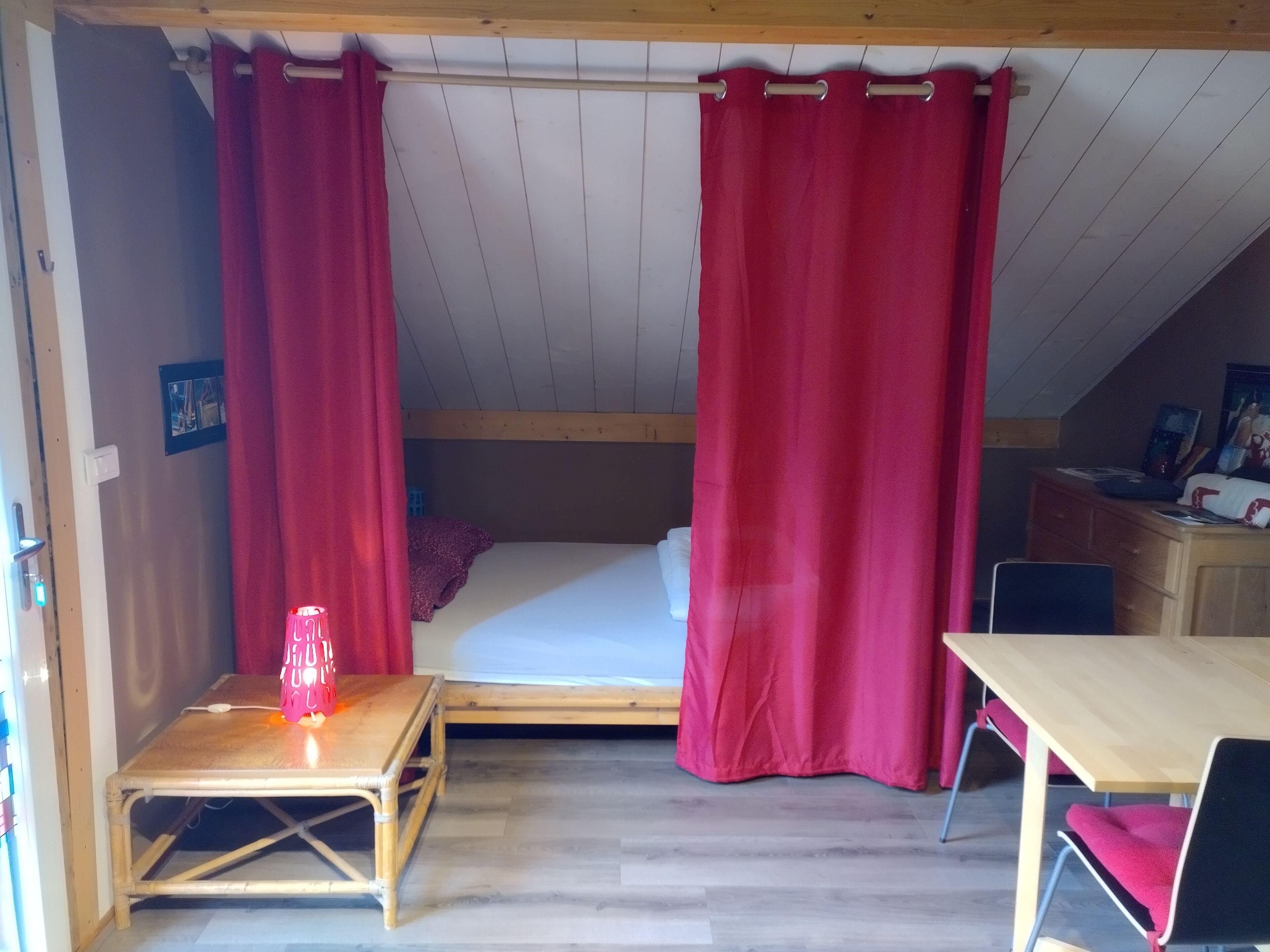 Ein kleiner, gemütlicher Raum mit einem Etagenbett, einem Holztisch, einem Stuhl und einem Tisch mit einer Kerze.