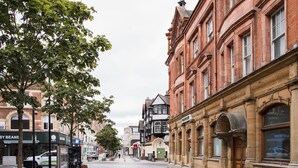 Een straat met historische gebouwen, een bankje en een bordje met de tekst 'Owen & Co'.