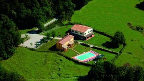 An aerial view of a property with a large house, a swimming pool, and surrounding green fields. - Appartamento Olive La Burraia (GAMBASSI TERME)