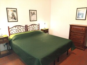 A bedroom with a bed, a dresser, a nightstand, and two wall-mounted pictures. - Appartamento Olive La Burraia (GAMBASSI TERME)