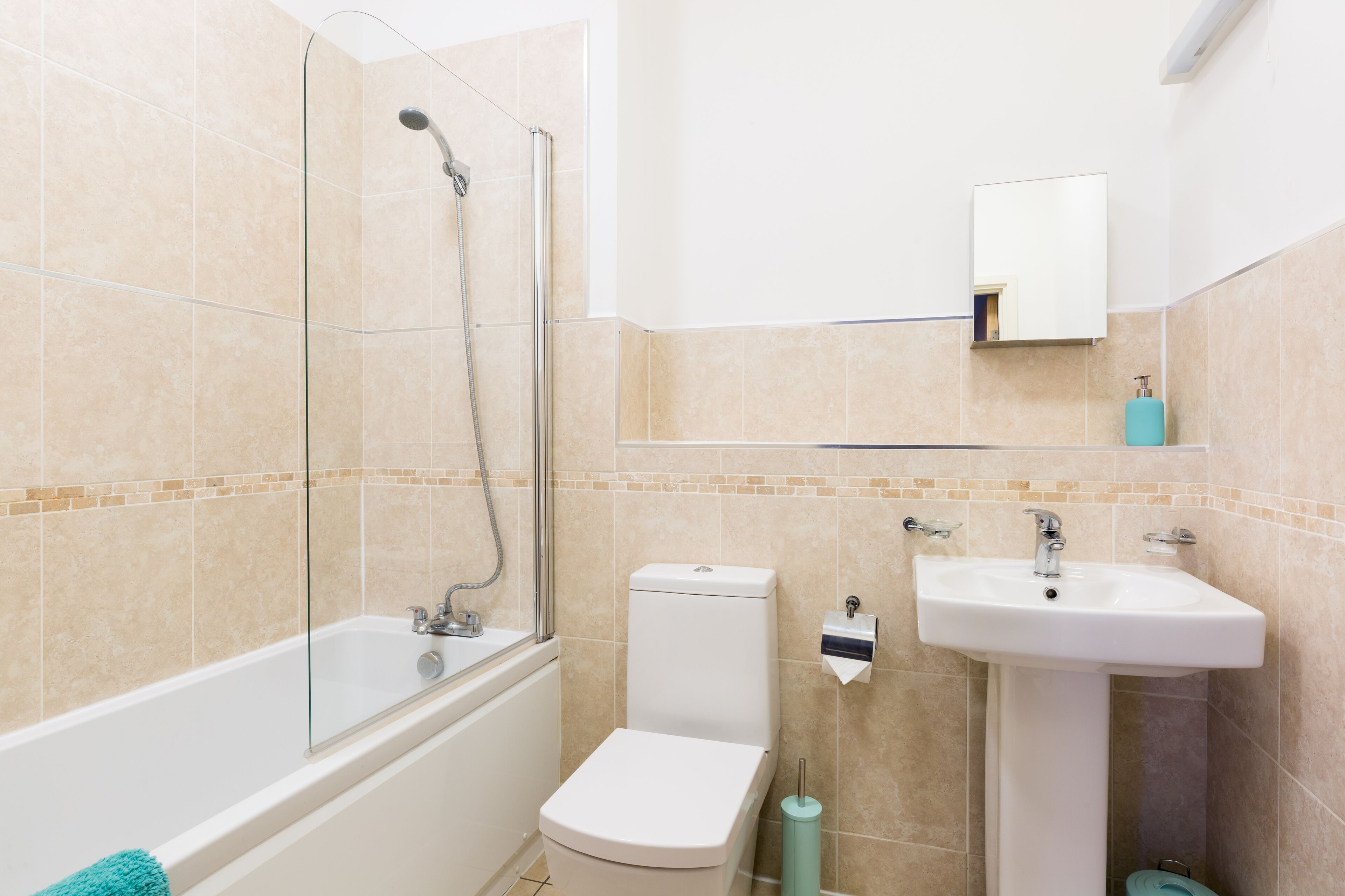 Une salle de bain moderne avec une douche à parois de verre, des toilettes blanches et un lavabo sur colonne.