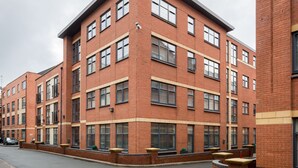 A multi-story brick building with a flat roof, large windows, and a corner entrance. - 2bed Apt -king Bed -free Parking - Family Friendly (Birmingham)