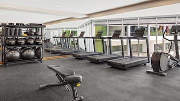 A modern gym with treadmills, a rowing machine, and a bench press.